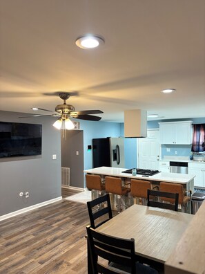 Enjoy meals in the kitchen and dining area with a central island, appliances, and a wooden table for four.