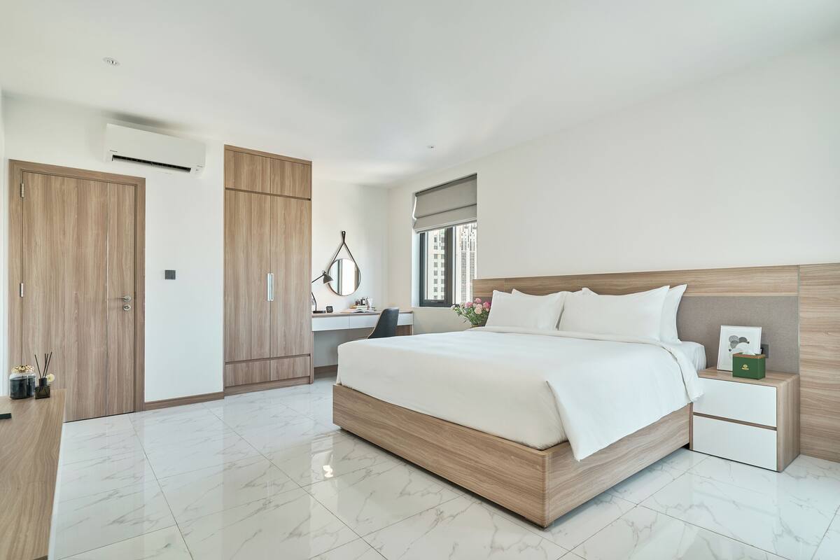 A modern bedroom with a large bed, a desk, and a wardrobe.