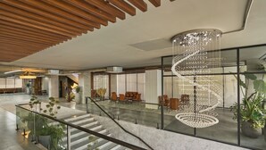 Un hall d’entrée spacieux, doté d’un escalier moderne, d’un grand lustre et de plusieurs coins salon.