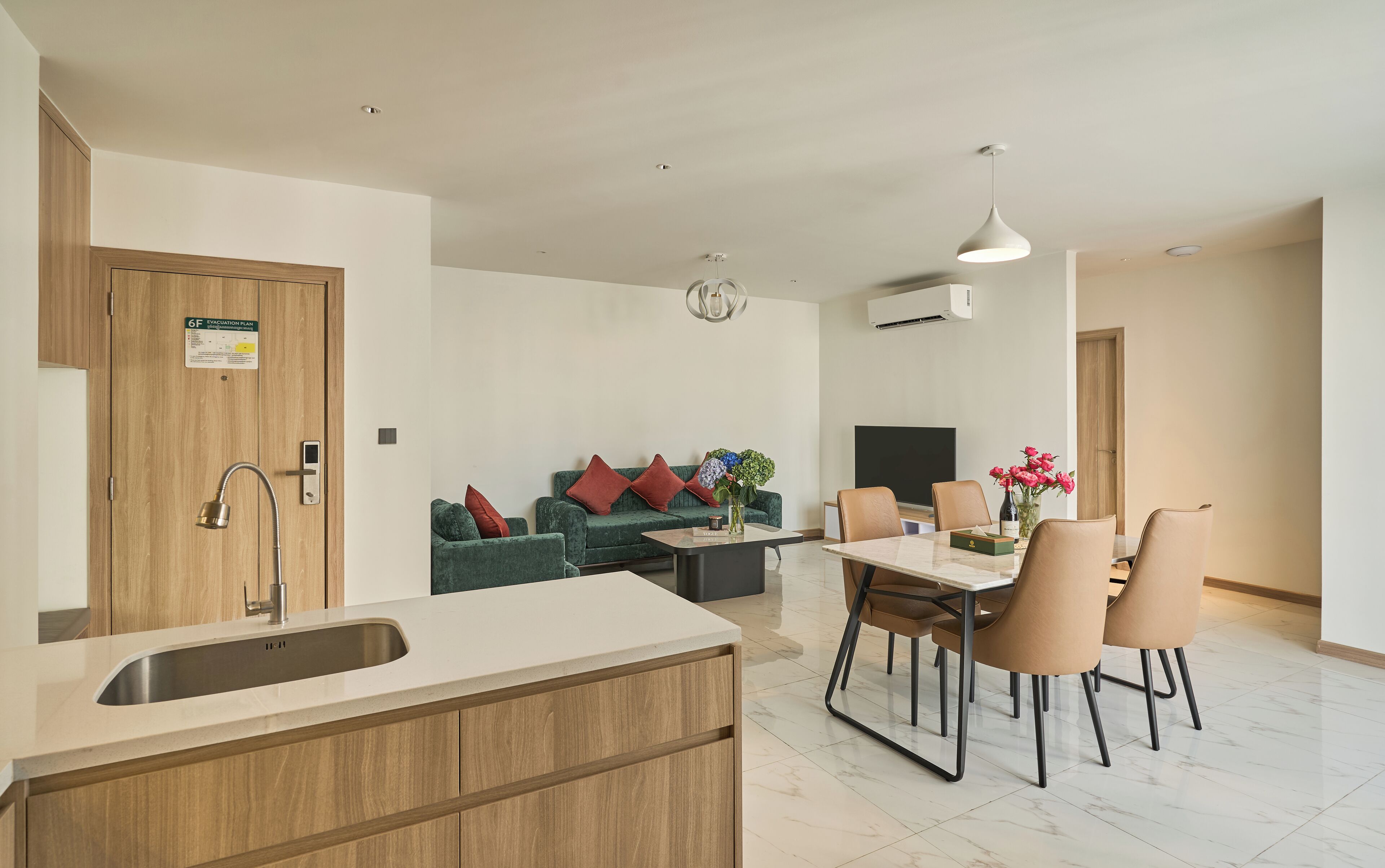 A modern apartment with a kitchen, dining area, and living room. It includes a sink, dining table, chairs, a sofa, and a TV.