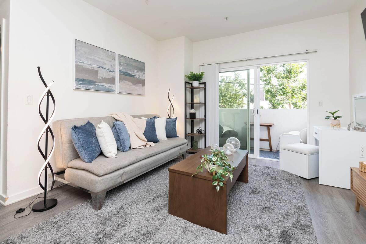 A modern living room with a sofa, coffee table, and a view through a glass door.