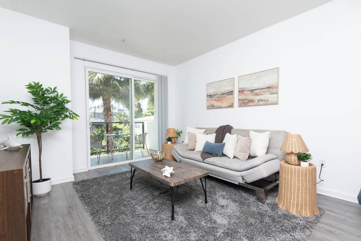 A modern living room with a grey sofa, a coffee table, a potted plant, and two wall-mounted paintings.