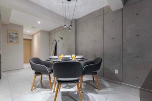 A modern dining area with a round table, four chairs, and a ceiling light fixture.