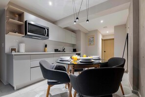 A modern kitchen with a microwave, cabinets, and a dining table with chairs.