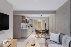 A modern living room with a grey sofa, a coffee table, and a TV mounted on the wall.