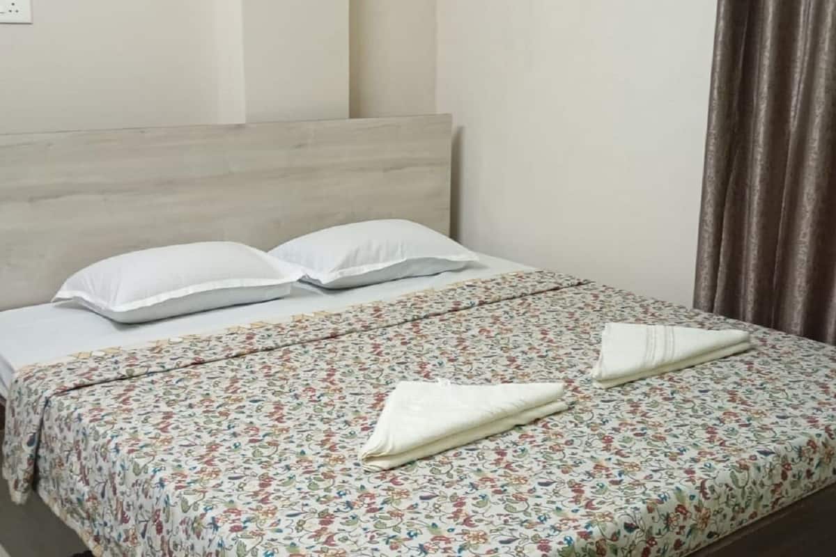 A neatly made bed with floral bedding, two pillows, and a folded towel.