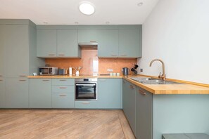 A modern kitchen with light blue cabinets, a wooden countertop, stainless steel appliances, and a copper faucet. - Stylish Home, Beautiful Views & Parking, Stroud (Brimscombe)