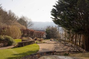 Un jardin avec un mur de pierre, une pelouse et des arbres.