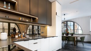 A modern kitchen with a large island, built-in appliances, and a dining area with a view of the city. - TiPToP Oxford St! Family+Couples Unique Chill Design Haven (London)