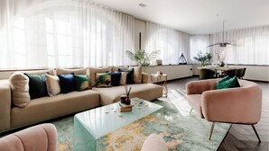 A modern living room with a beige sofa, a glass coffee table, and a pink armchair. - TiPToP Oxford St! Family+Couples Unique Chill Design Haven (London)