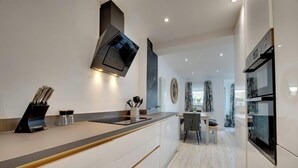 A modern kitchen with a central island, built-in oven, and a dining area with a view. - Staithes House (Gateshead)