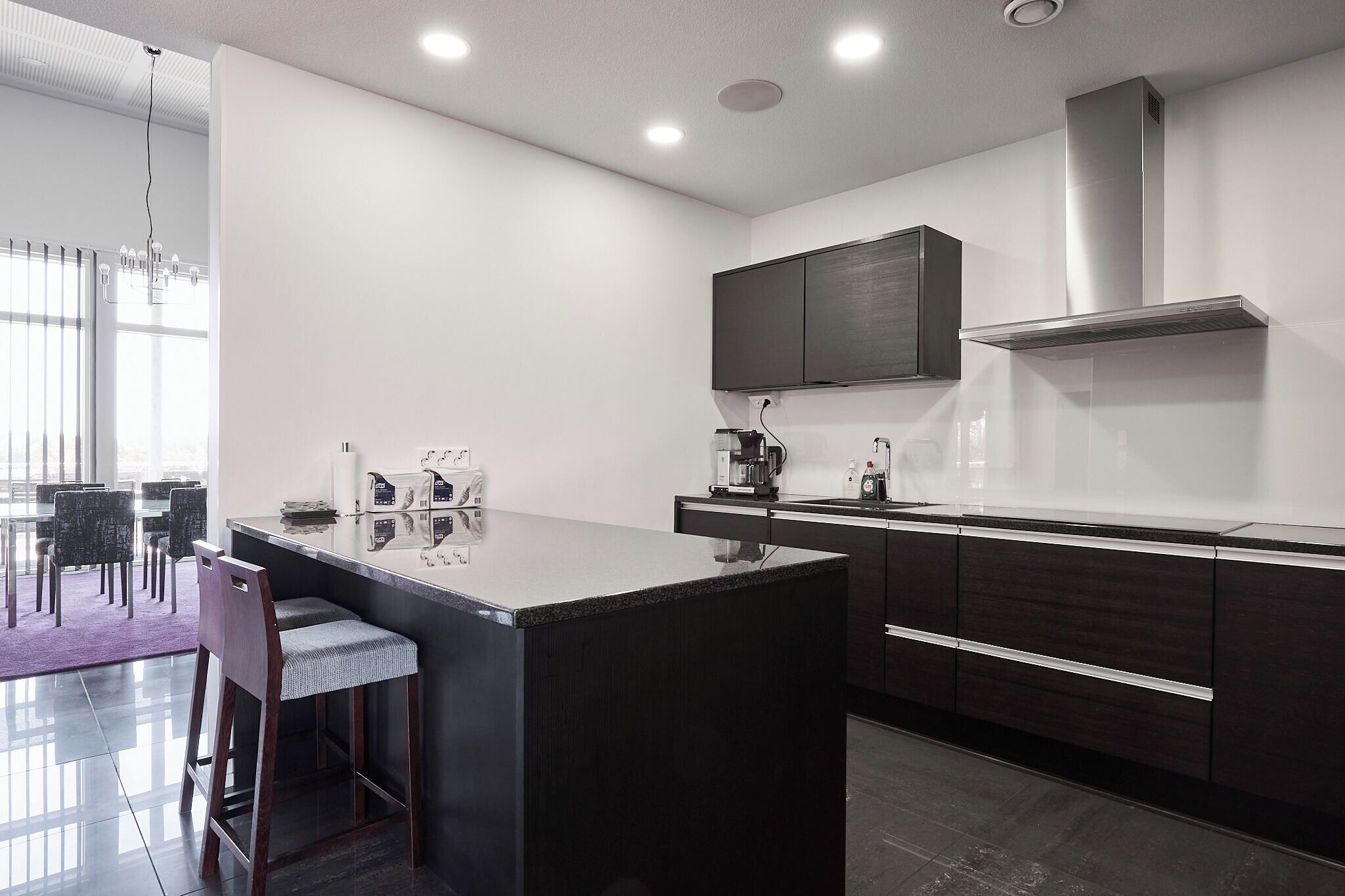 A modern kitchen with a central island, dark cabinetry, and a built-in microwave.