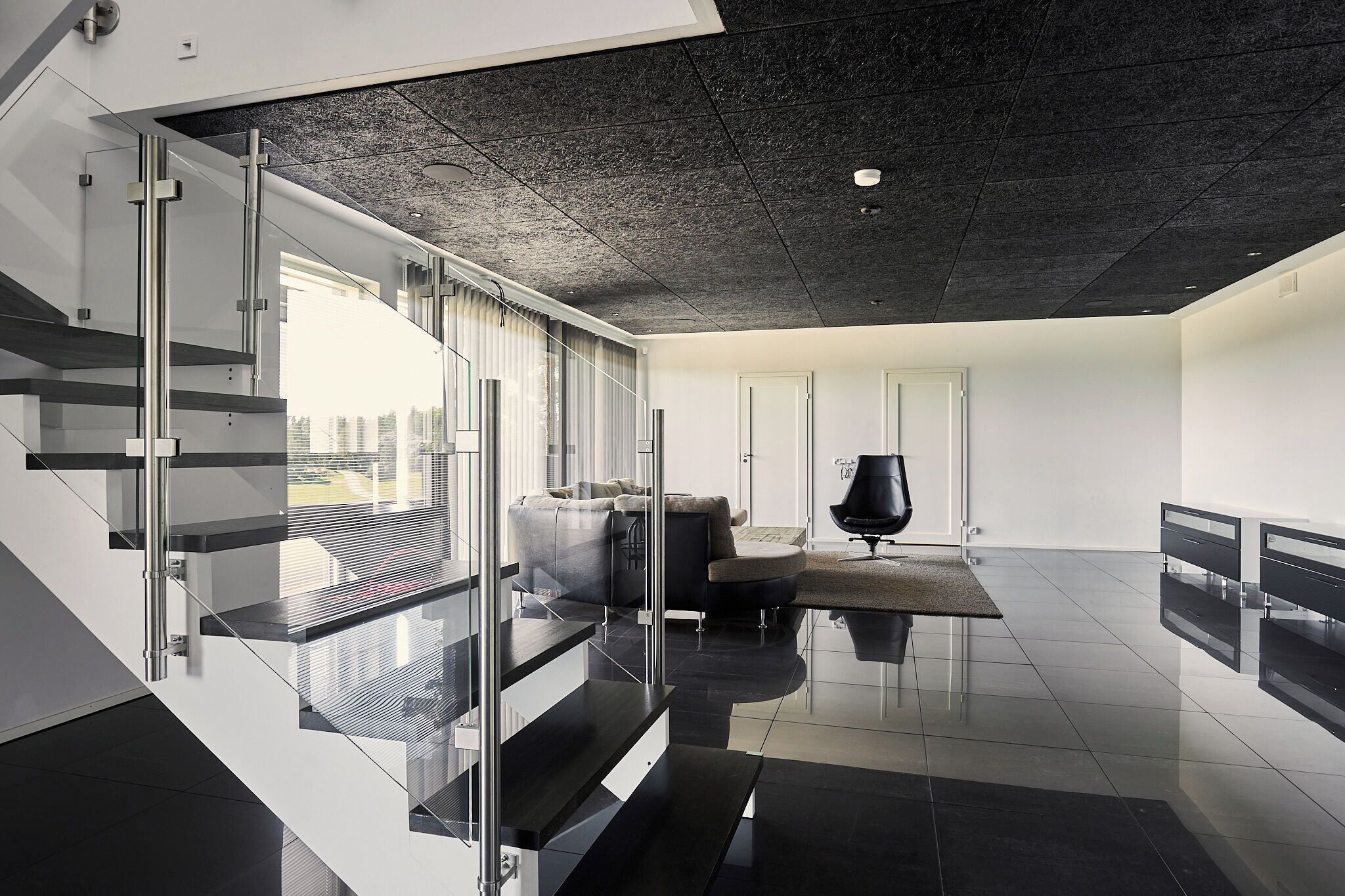 A modern interior with a glass staircase, a sofa, and a chair.