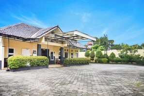 A building with a tiled roof, a covered entrance, and a paved courtyard. - Hotel O Pekalongan Near Pasar Batik Setono Formerly Hotel Puspa Indah (Pekalongan)