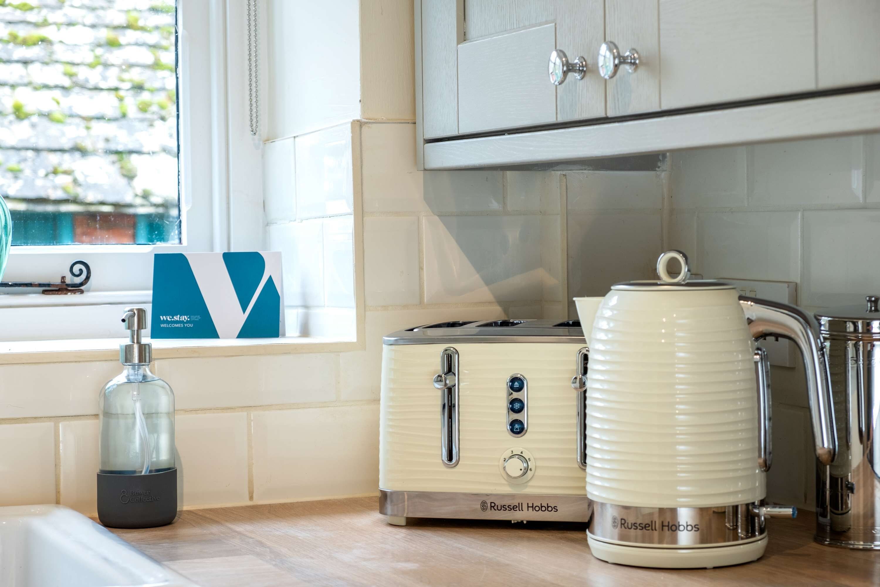 A kitchen with a vintage toaster, a kettle, and a soap dispenser on the counter.