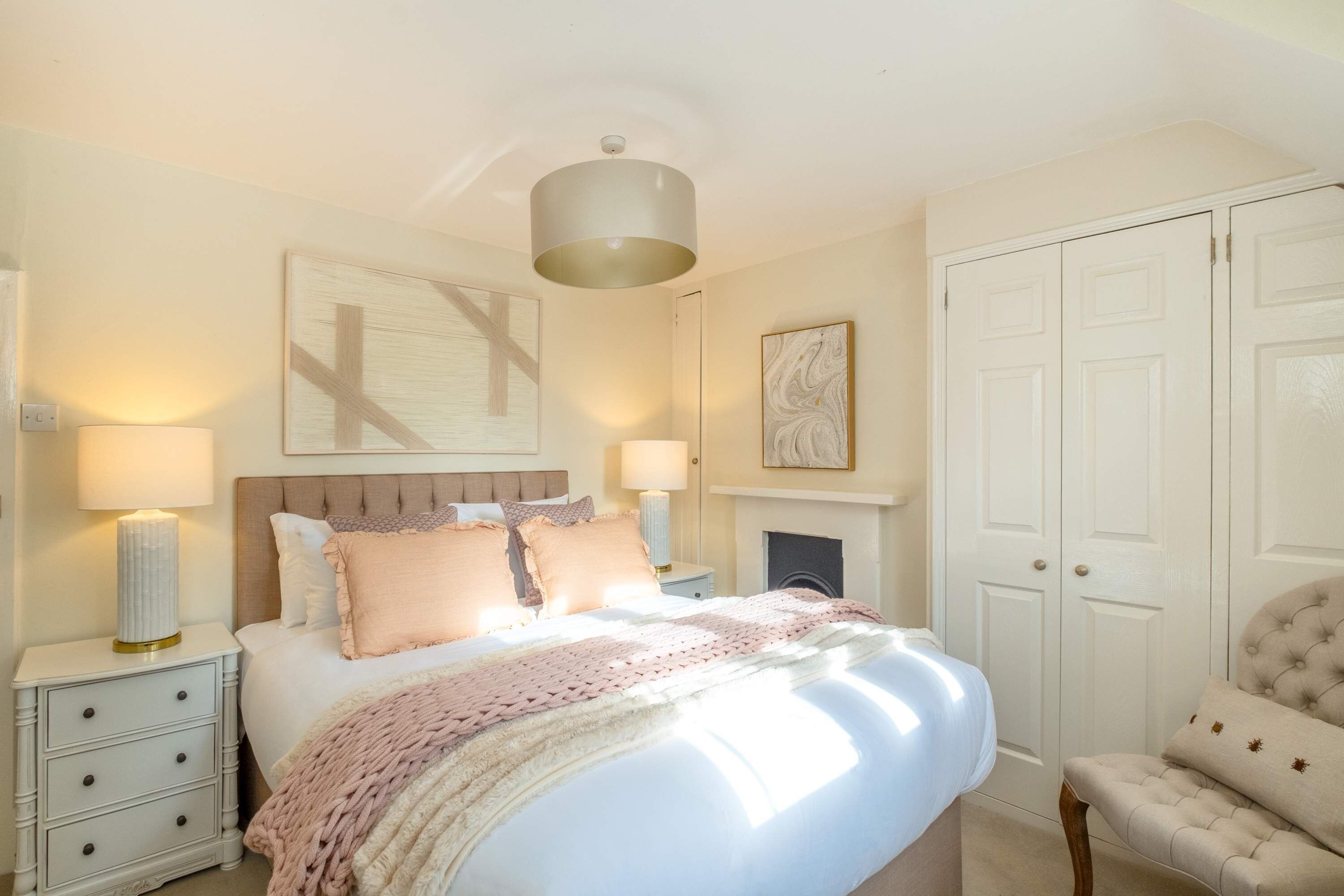 Une chambre à coucher avec un grand lit, des lampes de chevet, une cheminée et une armoire.