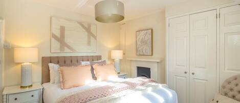 Une chambre à coucher avec un grand lit, des lampes de chevet, une cheminée et une armoire.