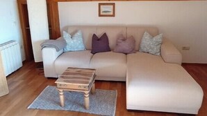 Ein Wohnzimmer mit einer Couch, einem Holztisch und einem gemusterten Teppich.