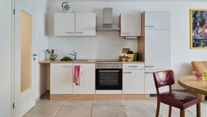 Moderni keittiö, jossa on valkoiset kaapit, sisäänrakennettu uuni ja puinen työtaso.