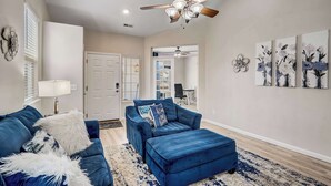A living room with a blue sofa, ottoman, and a ceiling fan.
