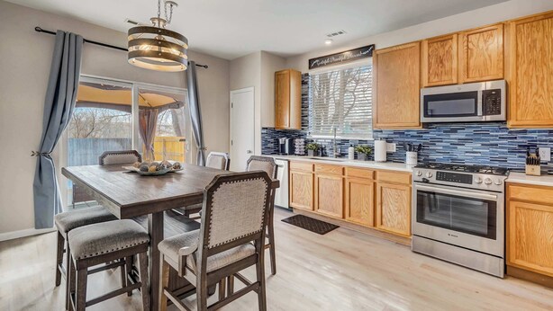 A modern kitchen with wooden cabinets, a Bosch oven, and a large window with blinds.