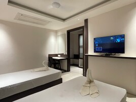 Una habitación de hotel con dos camas individuales, un escritorio, una silla, un televisor y un espejo.