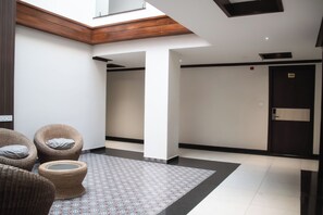 A modern hotel lobby with wicker furniture, a patterned floor, and a door marked 3005. - SV Grand (Mettupalayam)