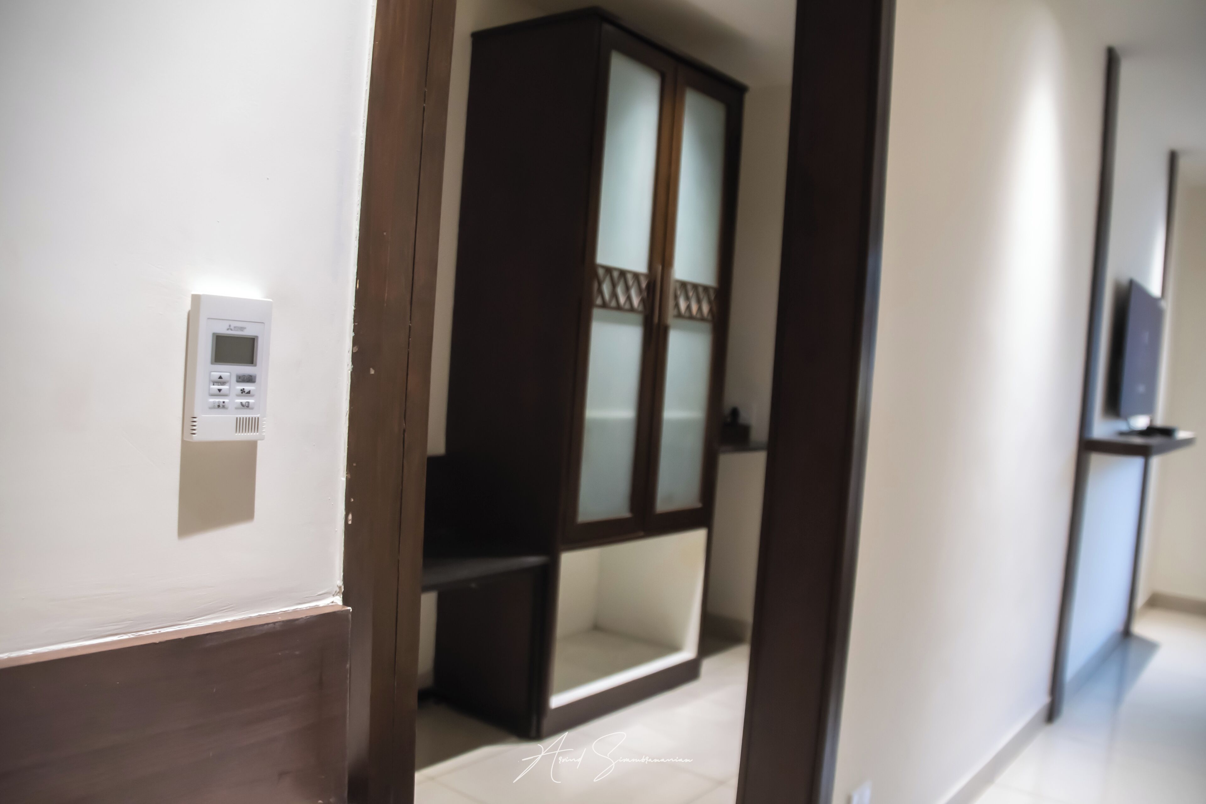 Un pasillo con un armario de madera y un panel de control en la pared.