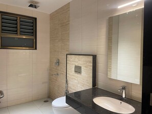 A modern bathroom with a toilet, sink, and shower. - SV Grand (Mettupalayam)