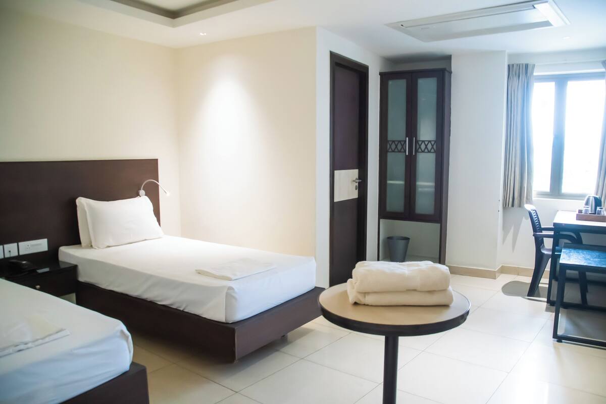 A hotel room with a bed, bedside table, and a small round table with towels.