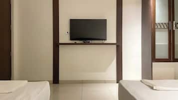 Habitación de hotel con dos camas, un televisor montado en la pared y un armario de madera.