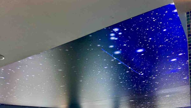 Una amplia piscina cubierta con diseño de cielo estrellado, ventanas grandes y un estilo arquitectónico moderno.