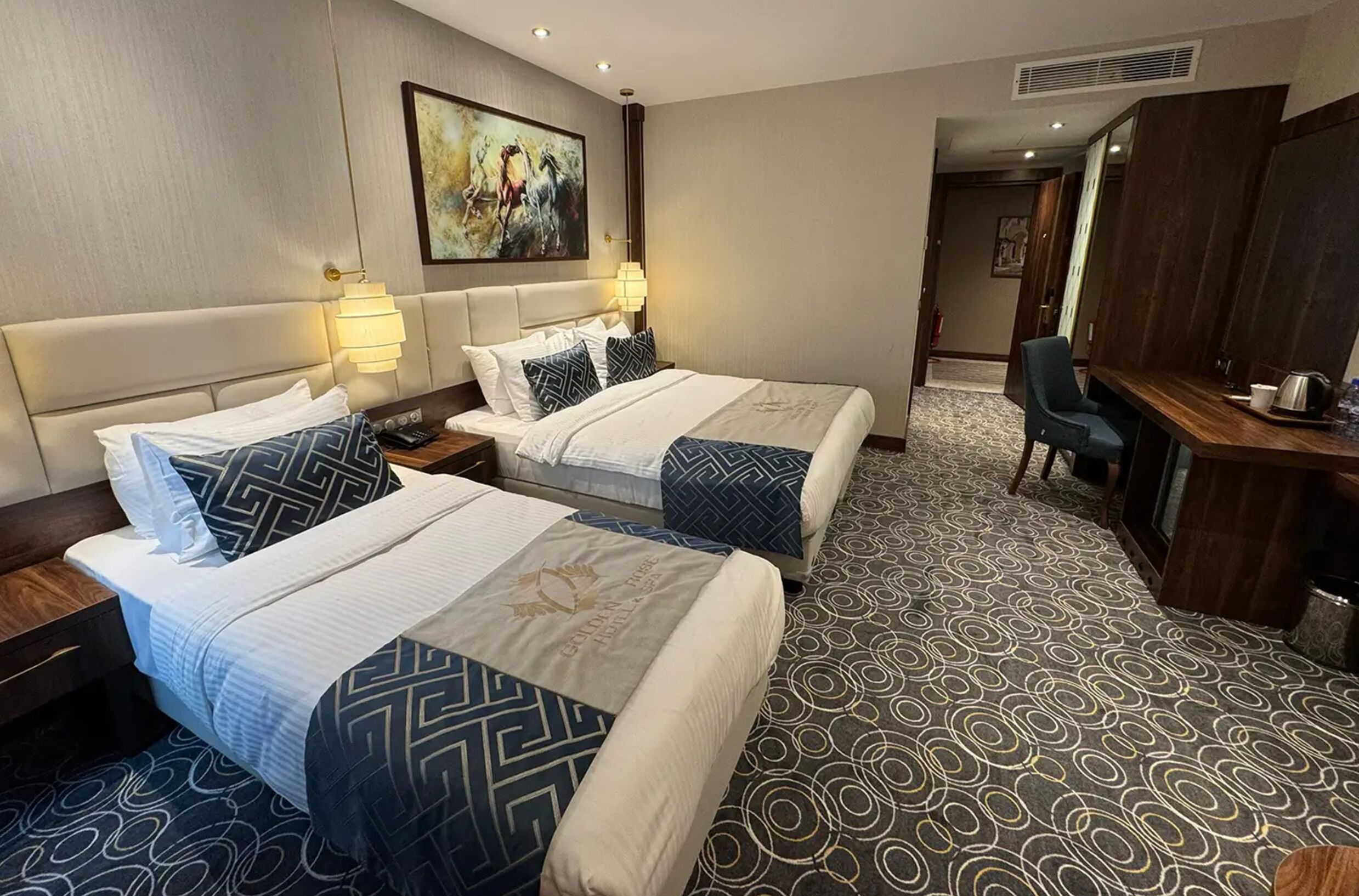 Una habitació d'hotel amb dos llits, una taula i una cadira.