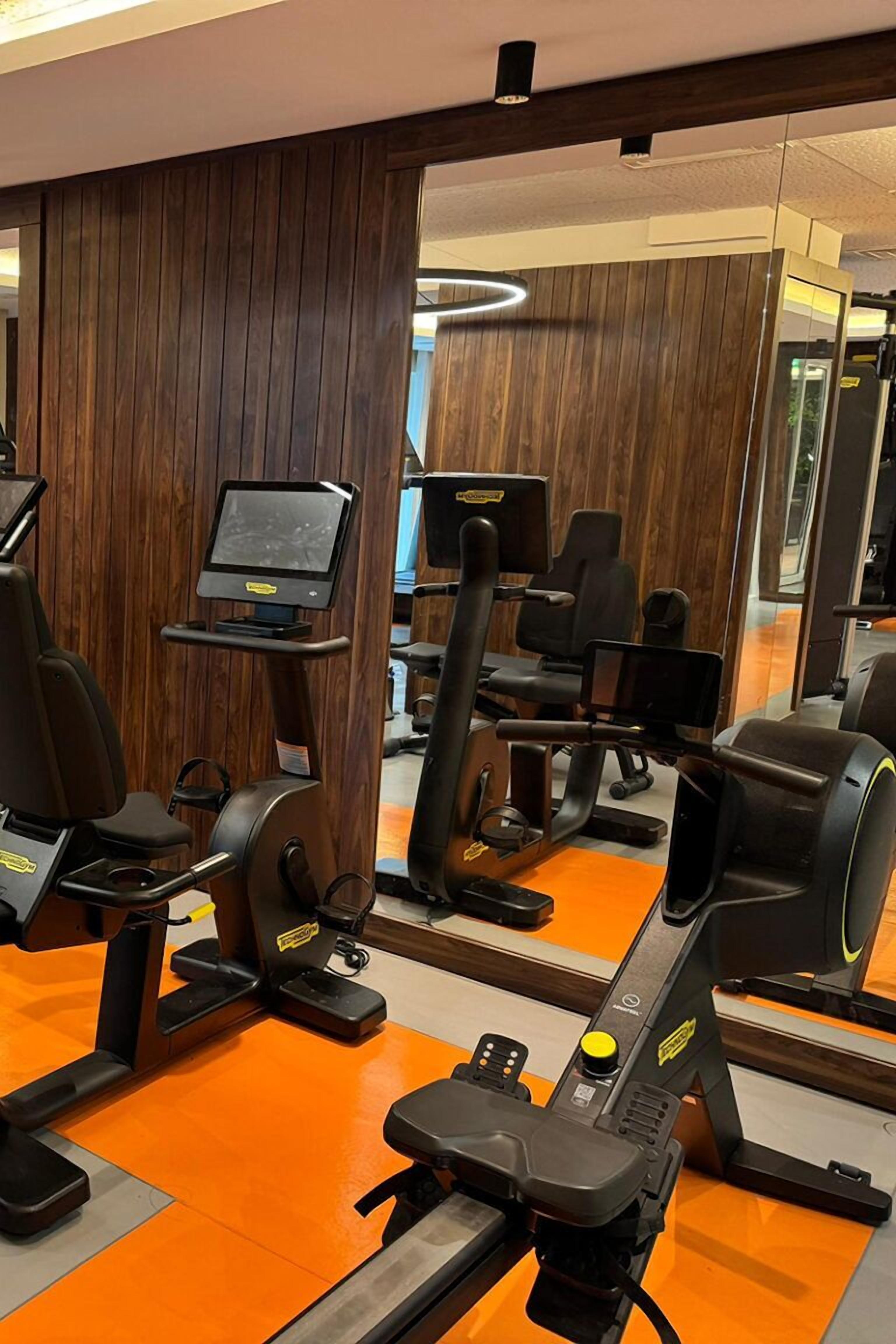 A gym with exercise equipment, a treadmill, and a mirrored wall.
