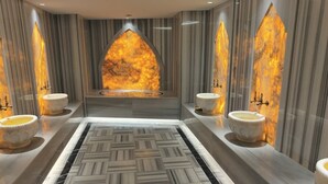Un baño lujoso con paredes de mármol, suelo con calefacción central y varios lavamanos de mármol blanco.