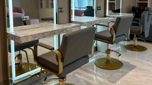 Un moderno salón de belleza con mostradores de mármol, sillas doradas y espejos grandes.