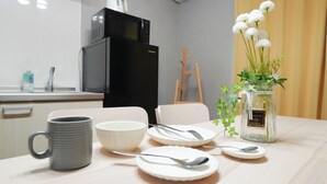 Eine Küche mit Kühlschrank, Mikrowelle und einem Esstisch, gedeckt mit Tellern, Schüsseln und einer Tasse.