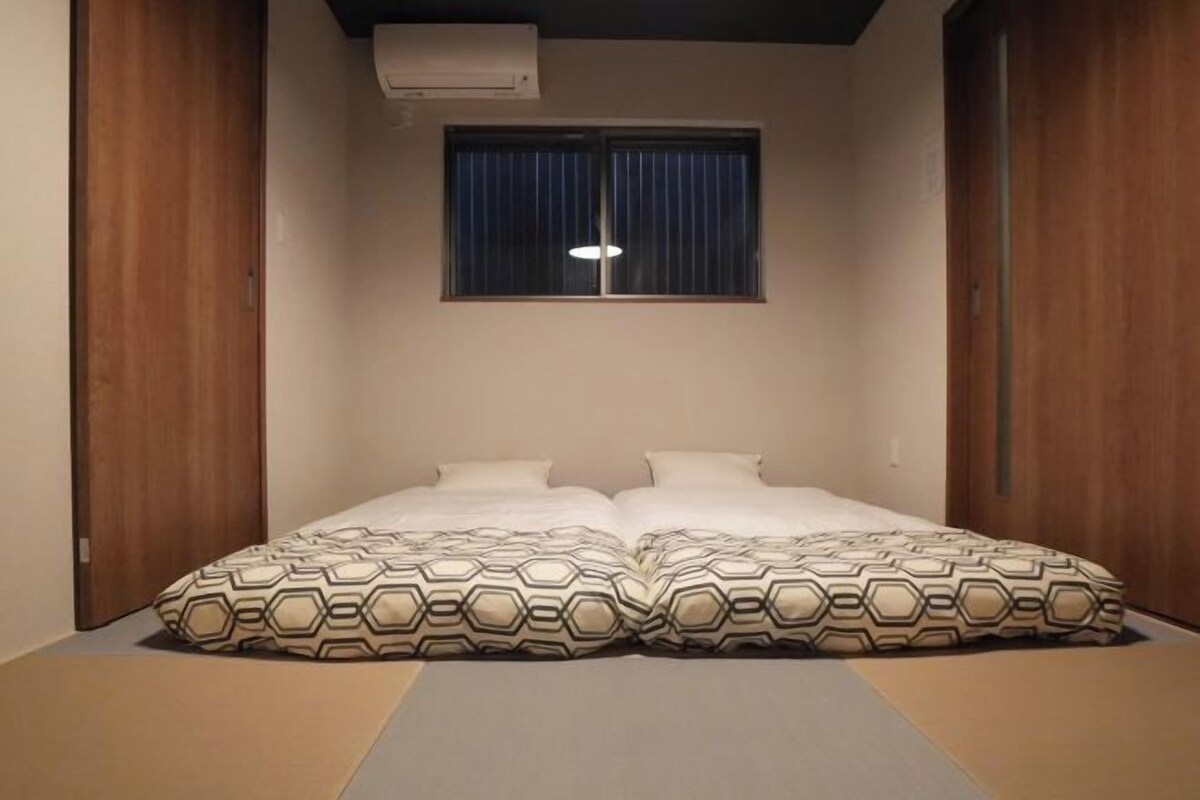 A room with a bed, a window with curtains, and an air conditioning unit.