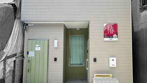 Ein Gebäude mit einer grünen Tür, einem Fenster und einem Schild mit japanischen Schriftzeichen.