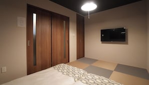A bedroom with a bed, a TV mounted on the wall, and a closet with sliding doors. - HANASTAY TSUBAKI (Osaka)
