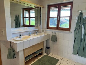 Enjoy a spacious bathroom with a dual sink vanity, large mirror, and convenient trash bin.
