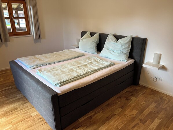 Restful retreat with a large bed, neatly made with linens and pillows, and a bedside table for convenience.