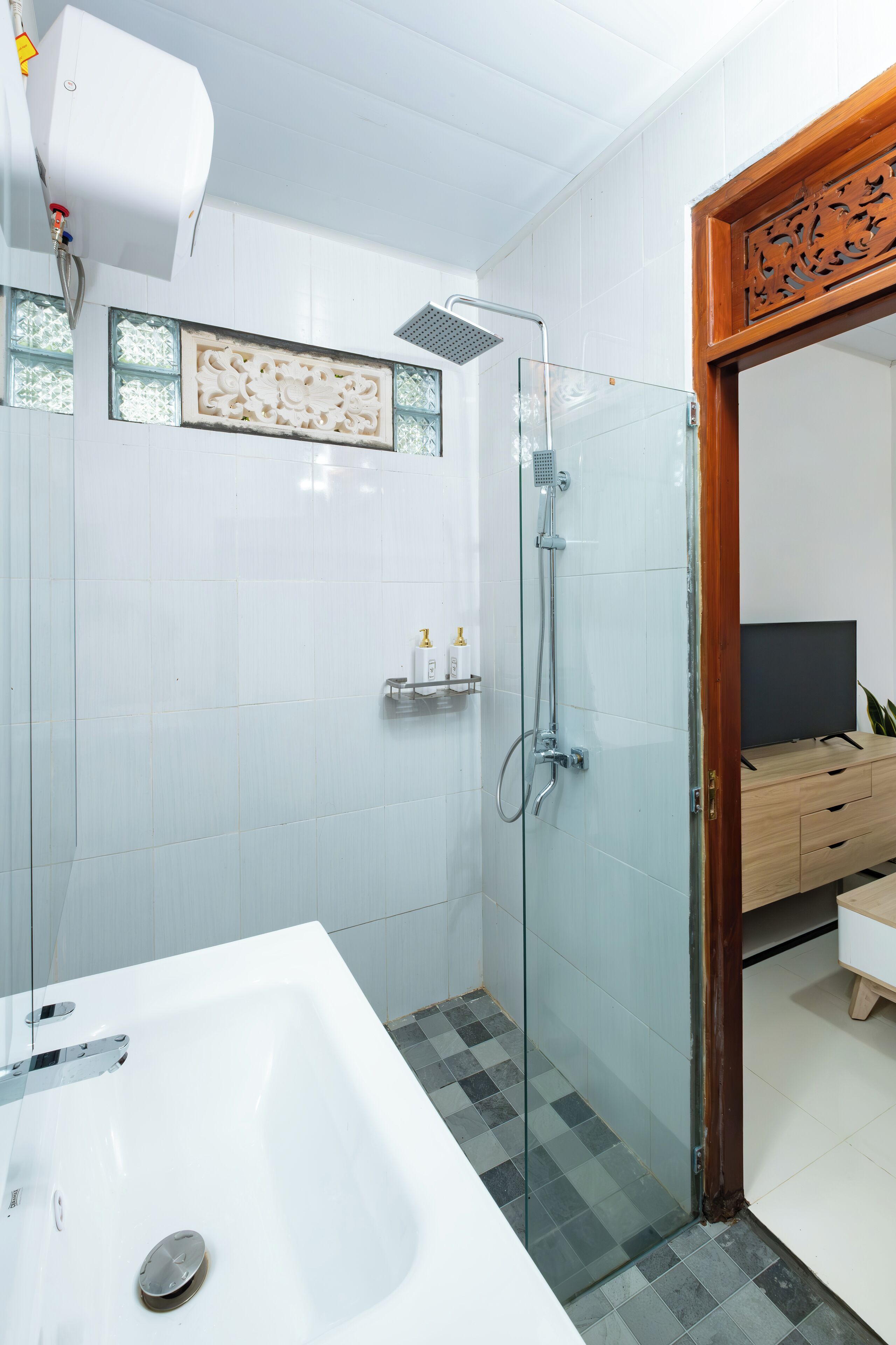 A modern bathroom with a glass shower enclosure, a white bathtub, and a wooden vanity with a television.