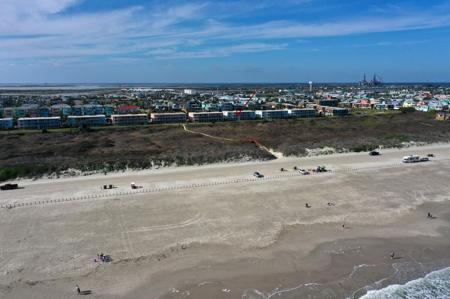 A coastal area with a beach, a road, and a residential area with colorful buildings.
