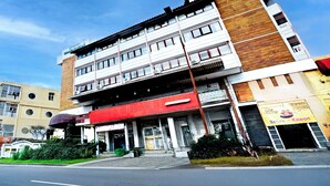 Un edificio de varios pisos con un toldo rojo, un escaparate visible y un cielo despejado.