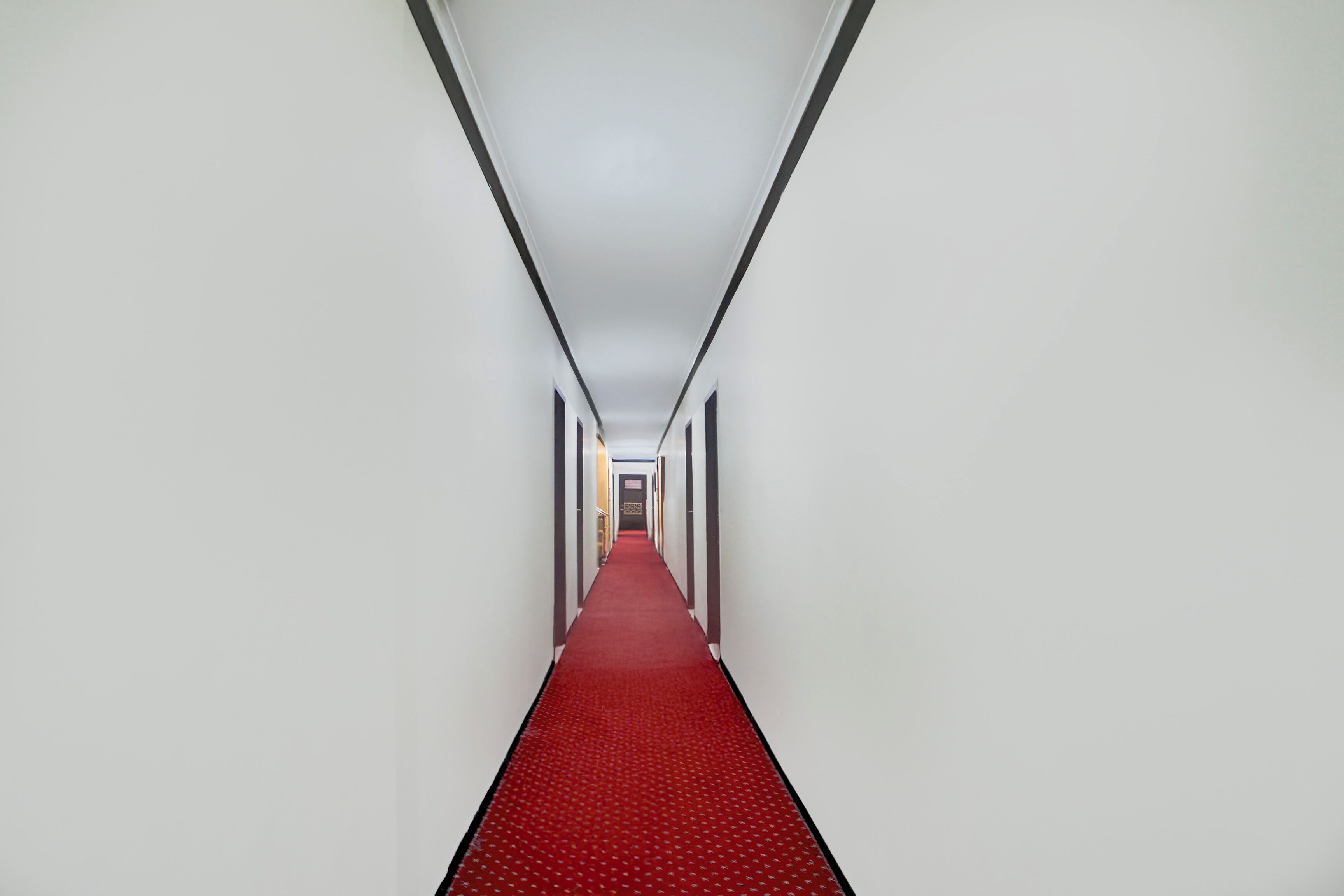 A long, narrow hallway with a red carpet and white walls.