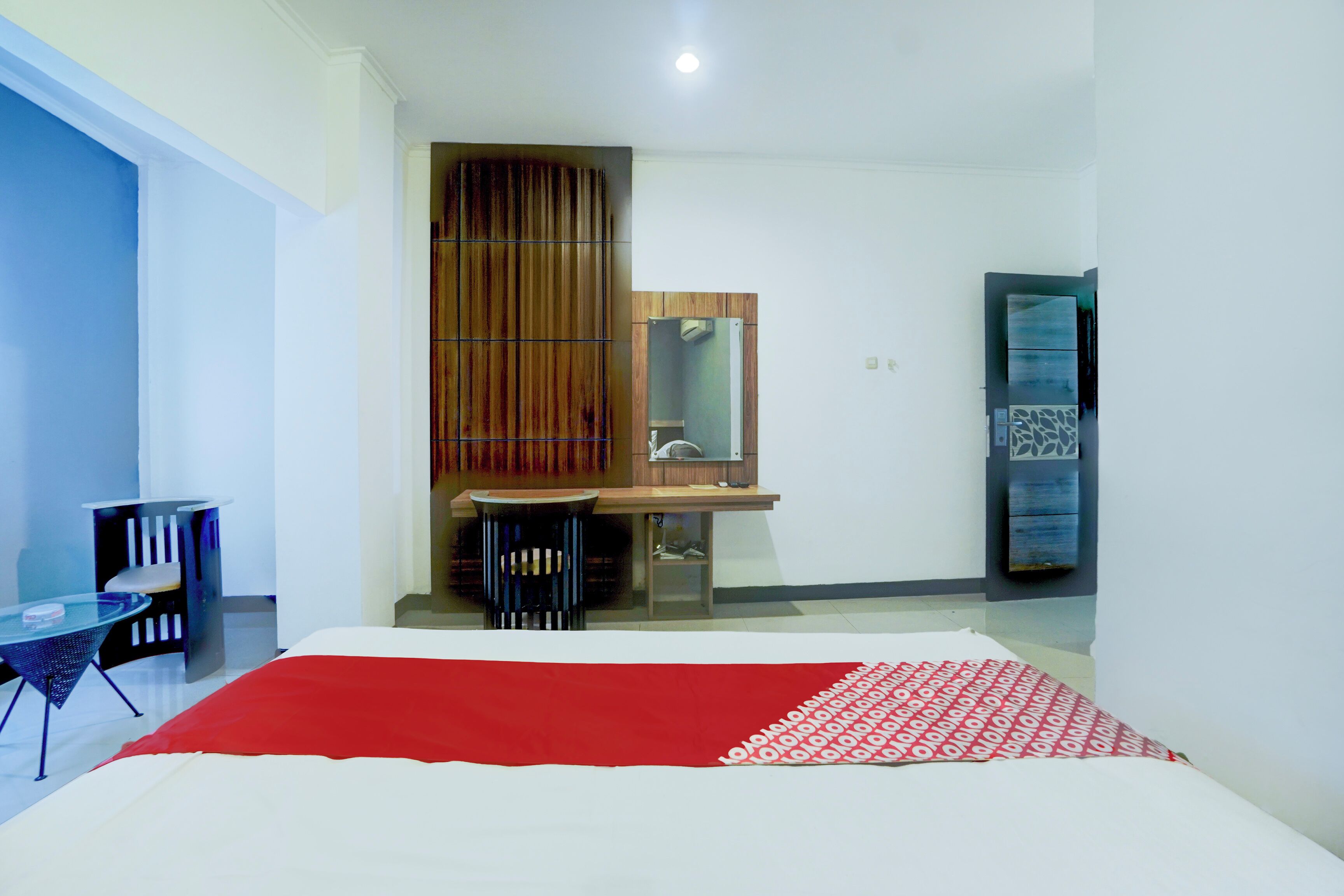 A bedroom with a bed, a desk, and a mirror.