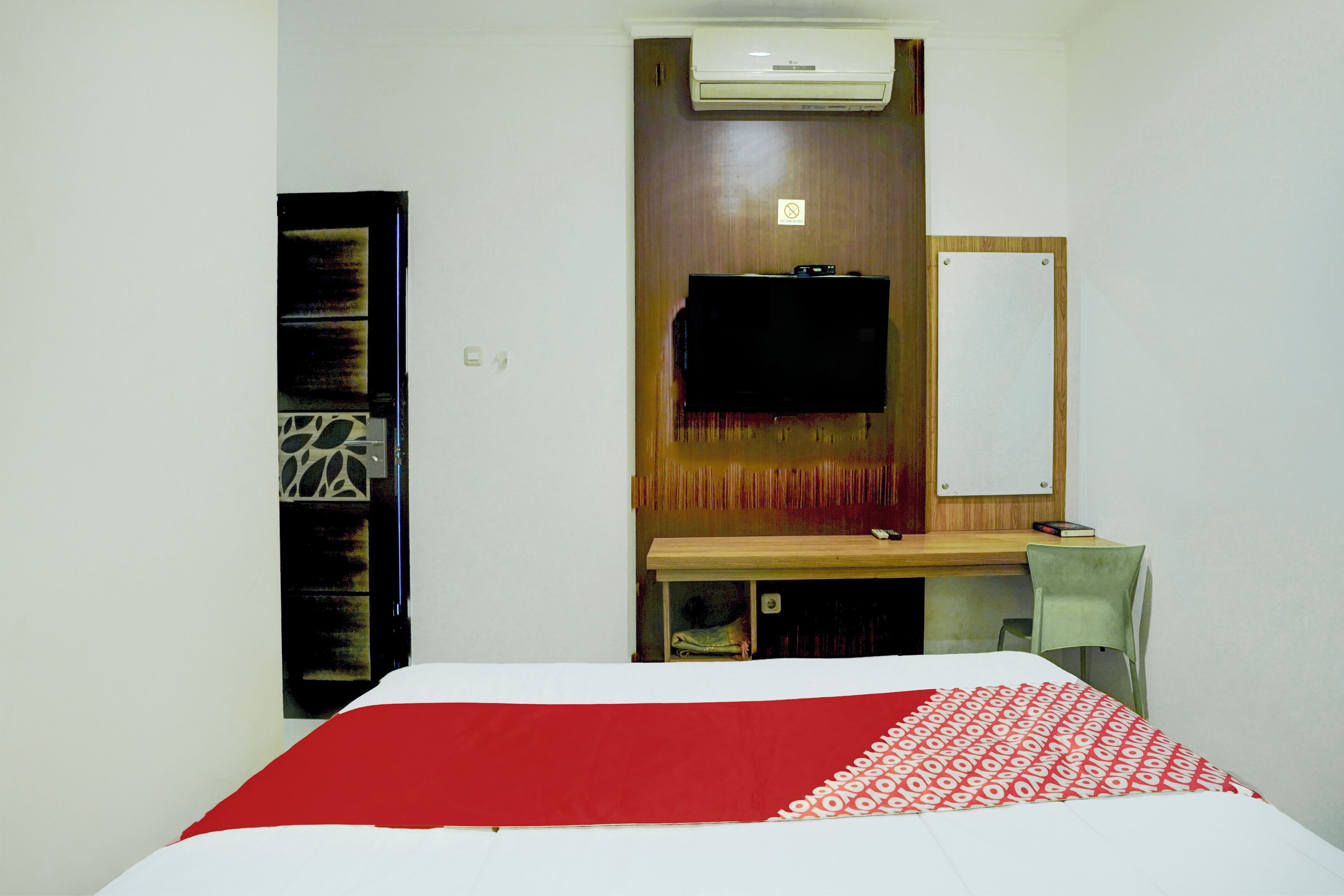 Una habitación de hotel con cama, escritorio, silla, televisor y armario.