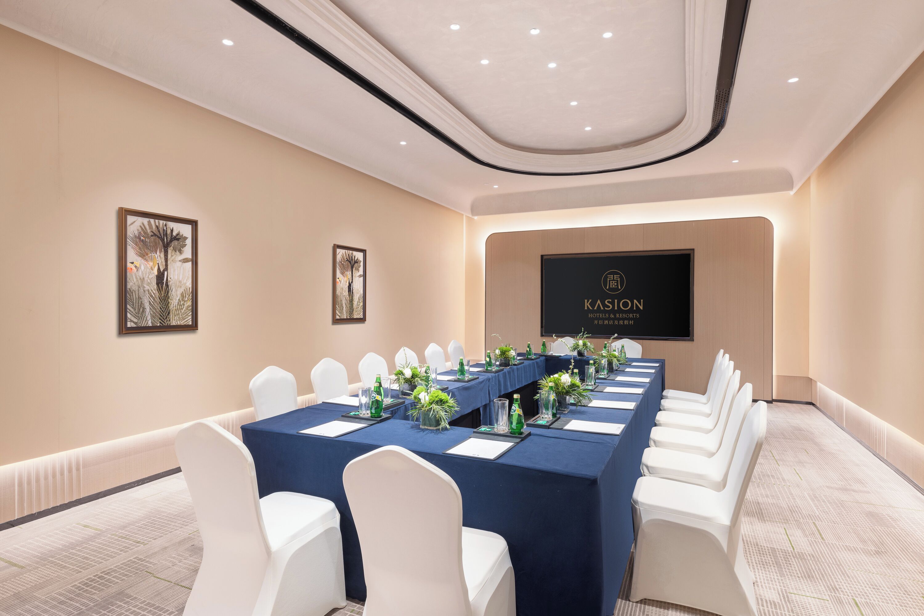 A conference room with a long table, white chairs, and a banner reading "KASION HOTEL & RESORTS".