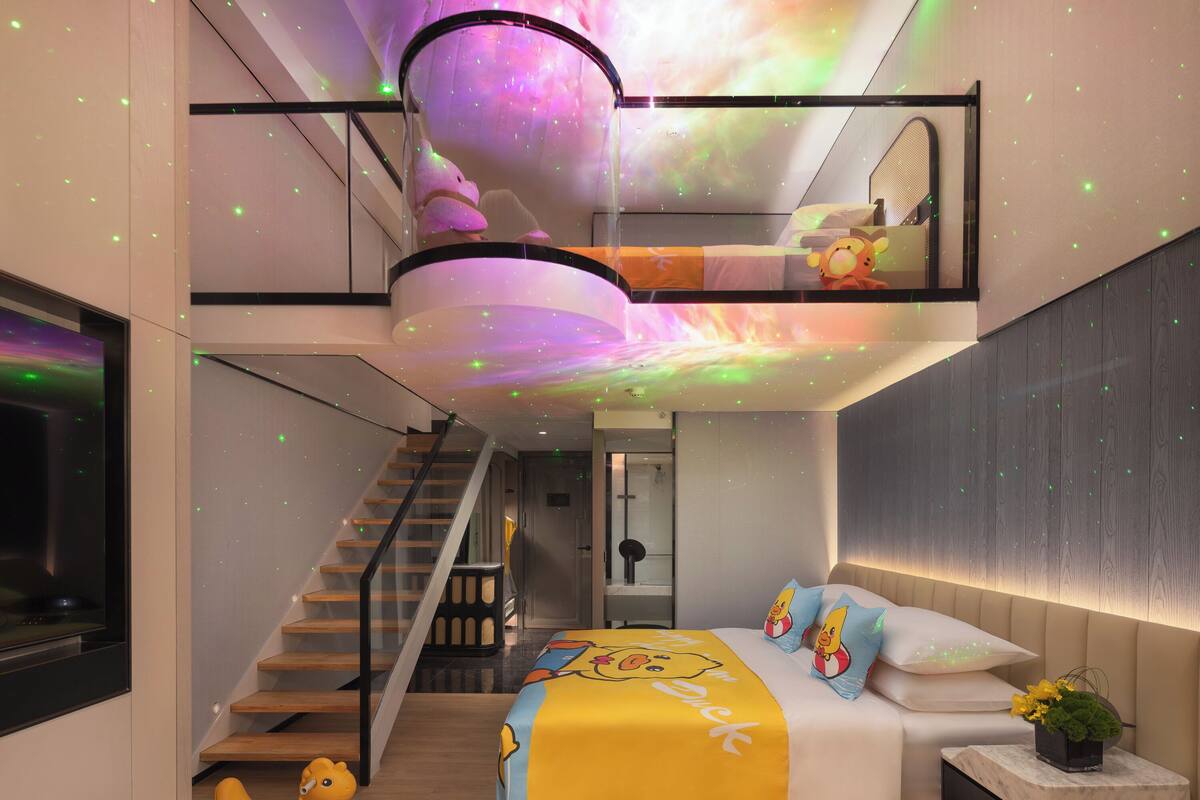 A modern bedroom with a bed, a nightstand, a window, and a staircase.